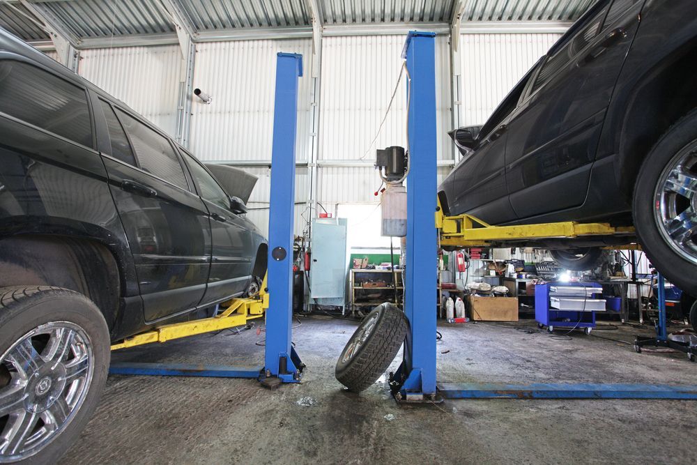 Two Black Suvs on Lifts in an Auto Repair Garage — Forster Smash Repairs in Forster, NSW