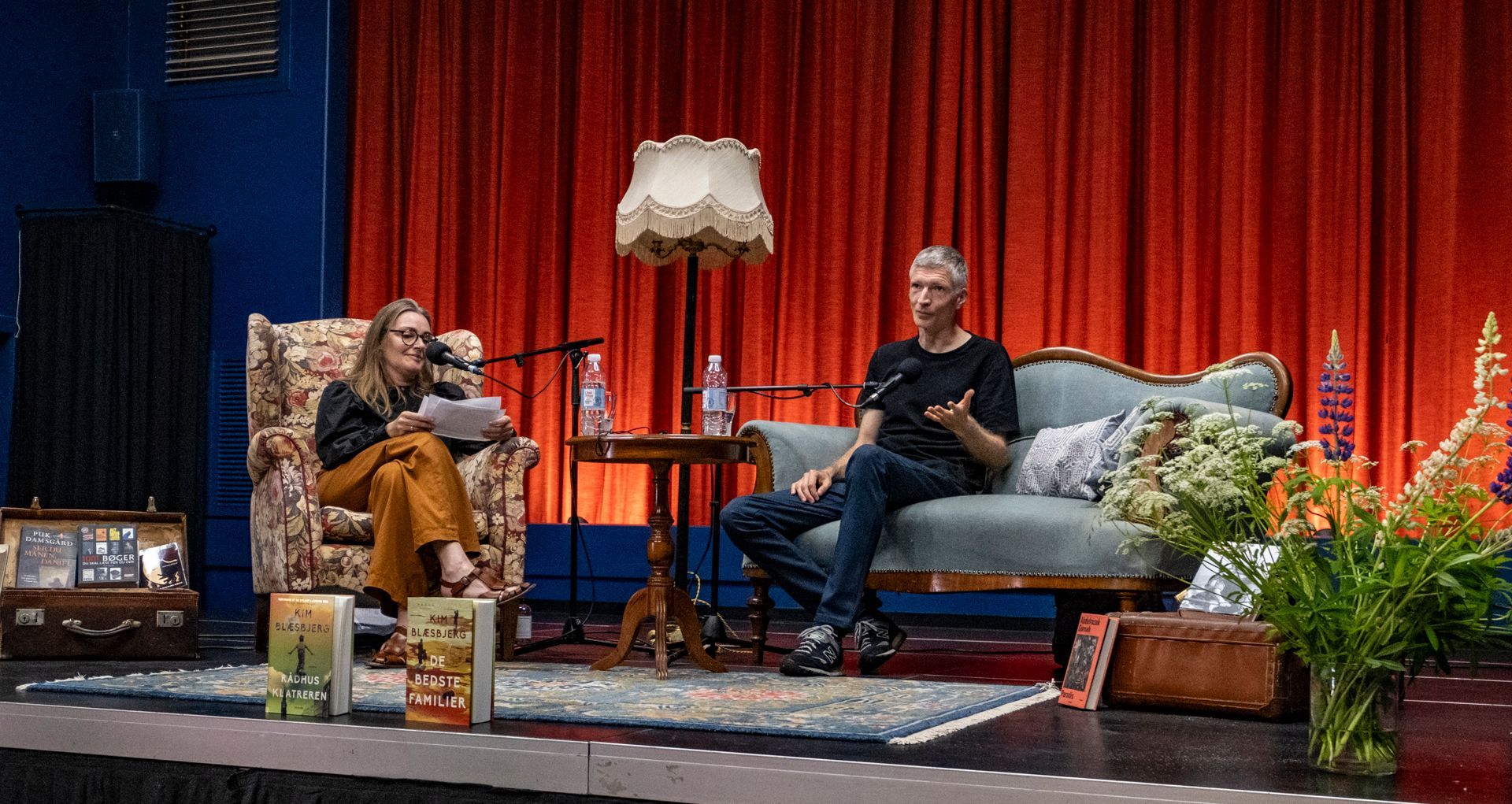 En mand og en kvinde sidder på en sofa på en scene.