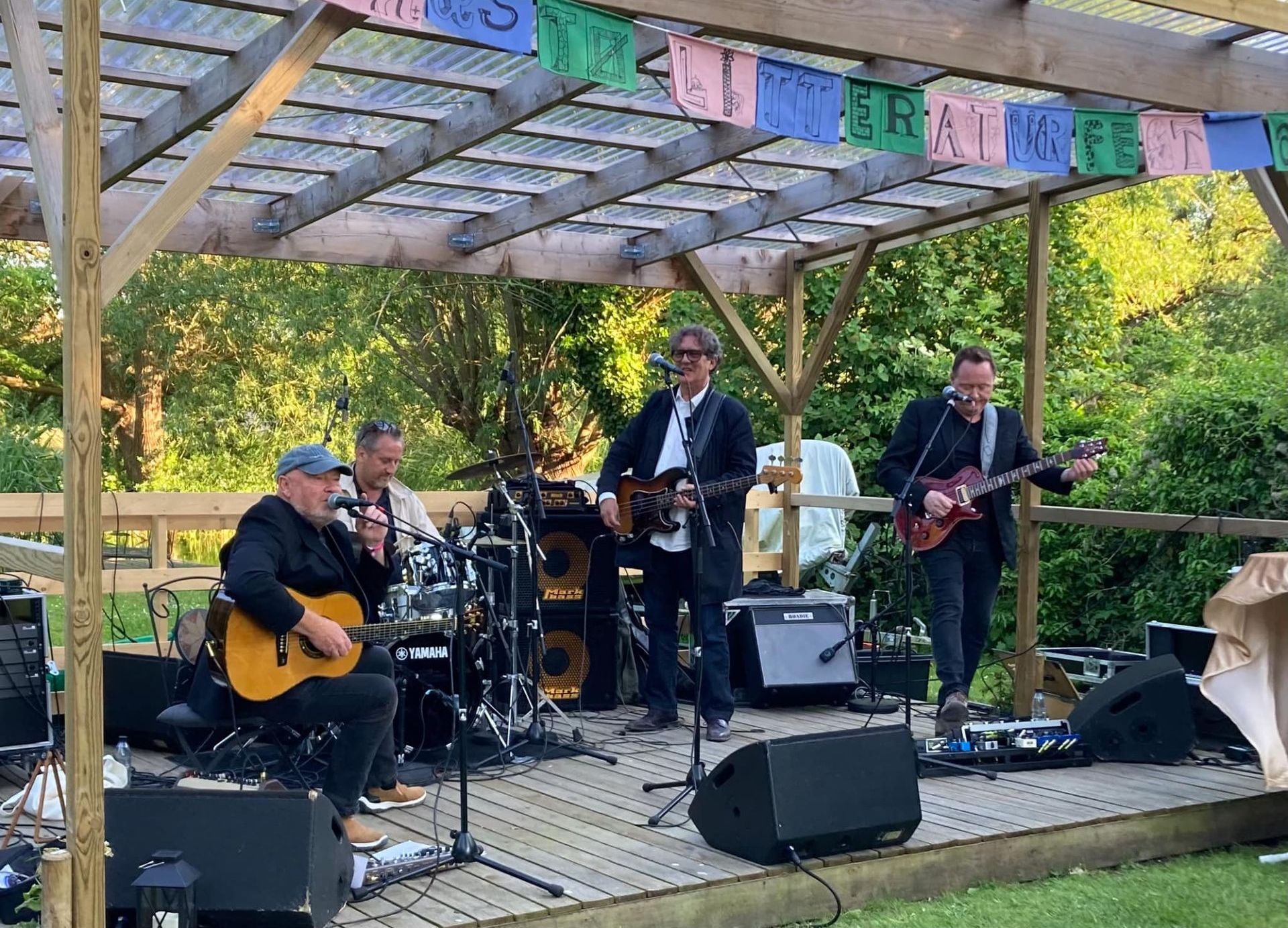 En gruppe mænd spiller guitar og synger på en scene.