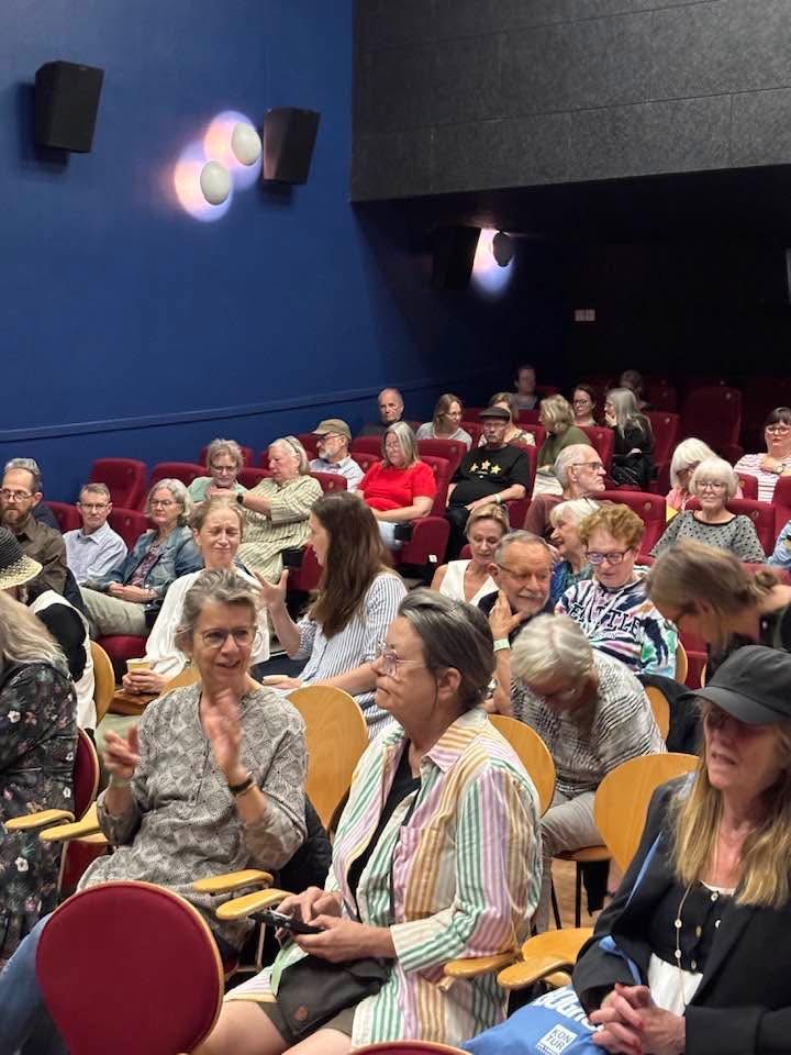En stor gruppe mennesker sidder på stole i en biograf