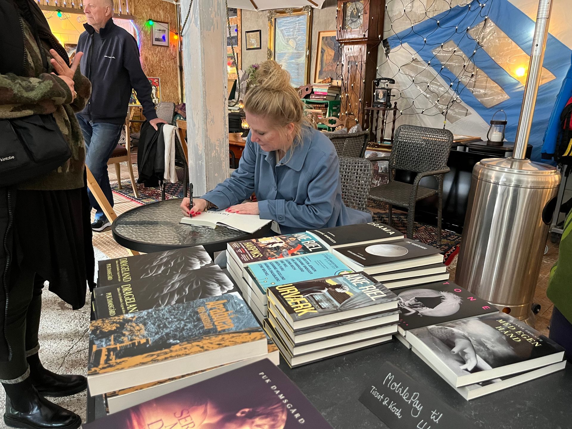En kvinde sidder ved et bord og signerer bøger.