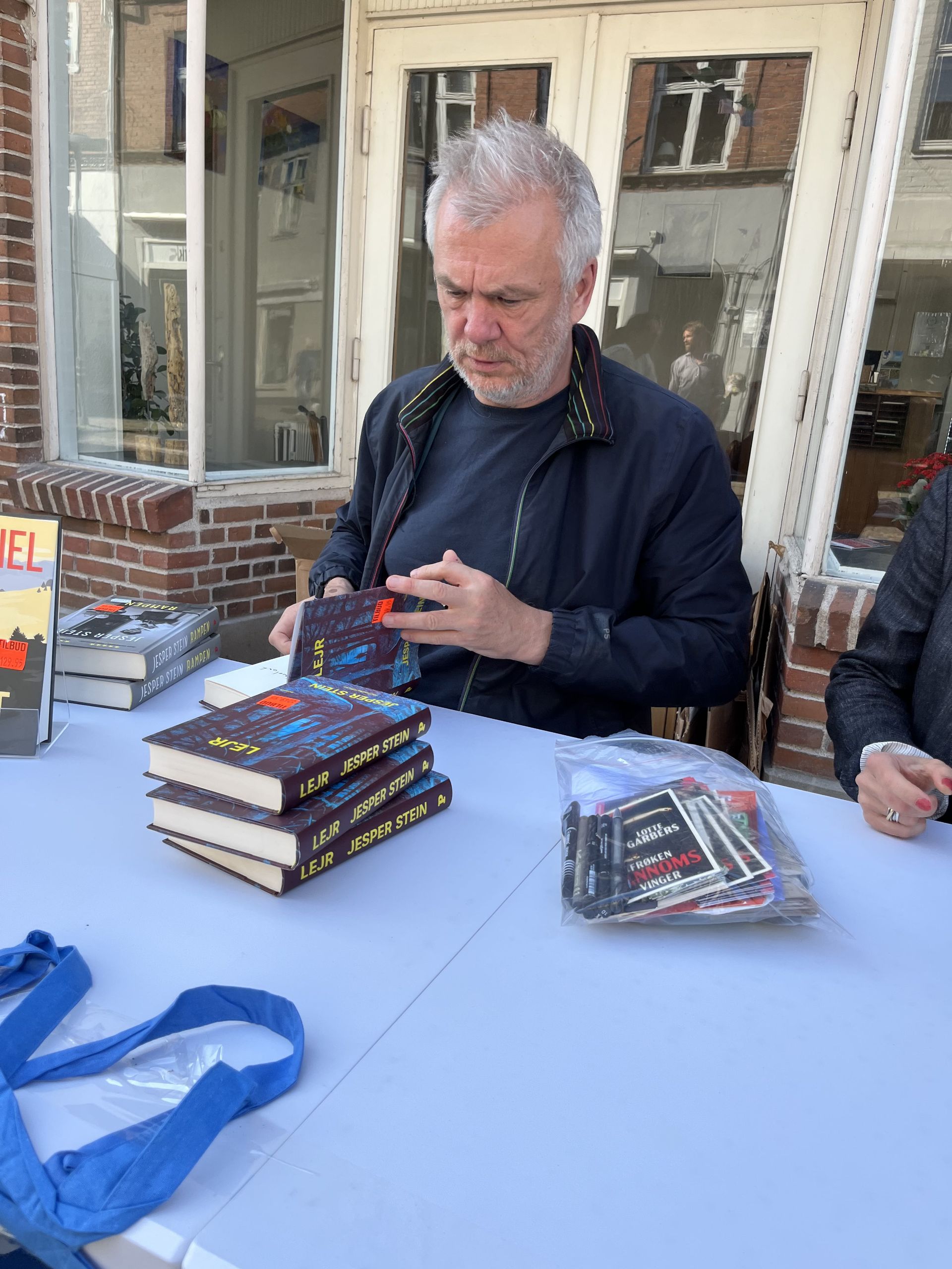 En mand sidder ved et bord og signerer bøger.