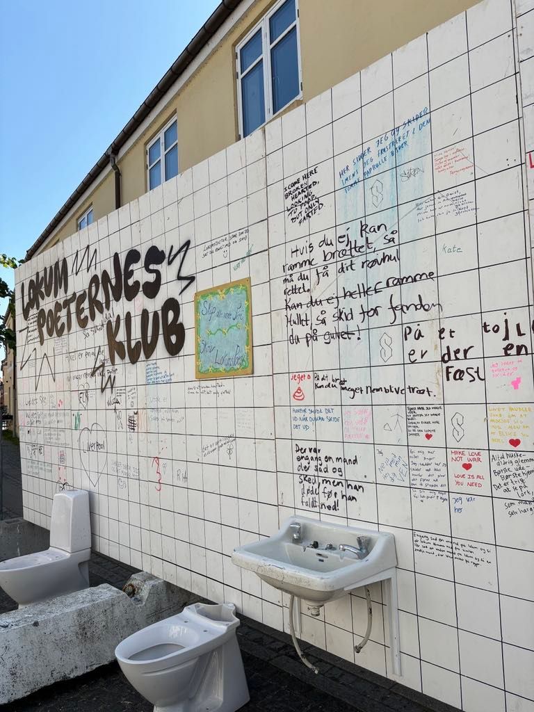 En væg med toiletter og en håndvask har graffiti på sig