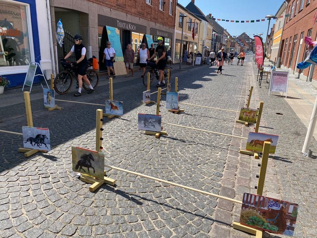 En gruppe mennesker går ned ad en brostensbelagt gade.