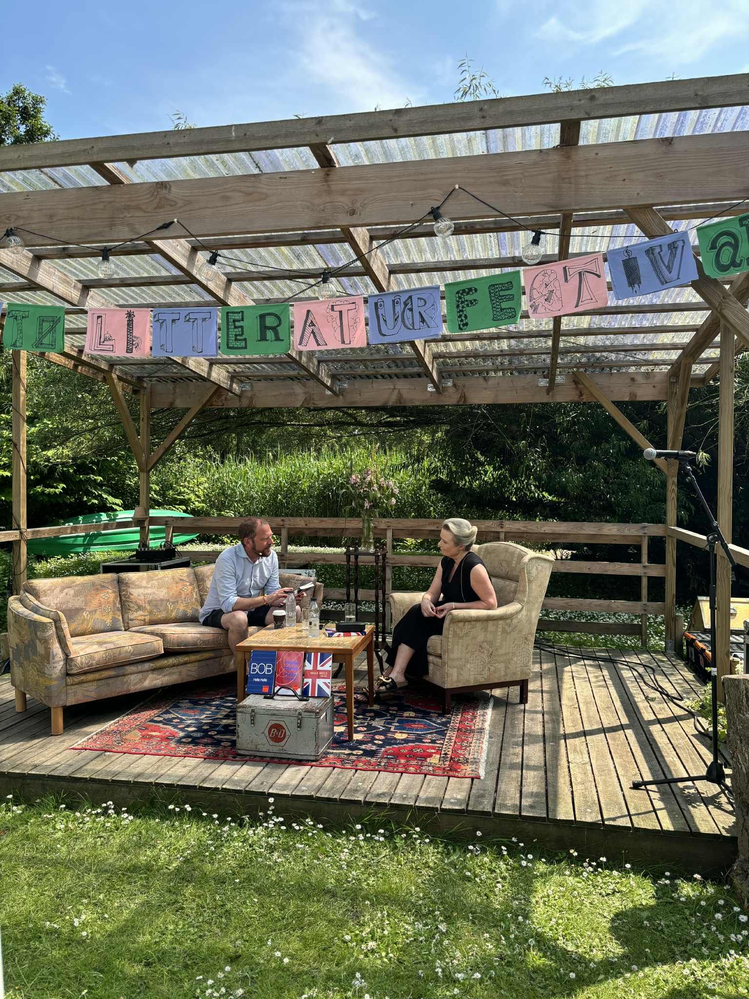 En mand og en kvinde sidder på en sofa under en pergola.