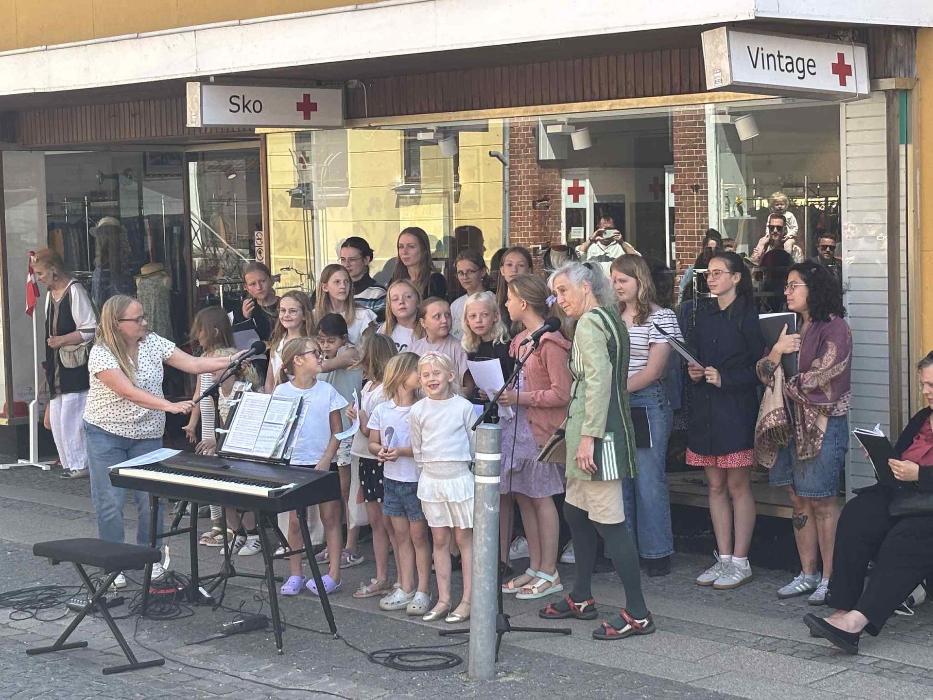 En gruppe mennesker synger foran en butik.