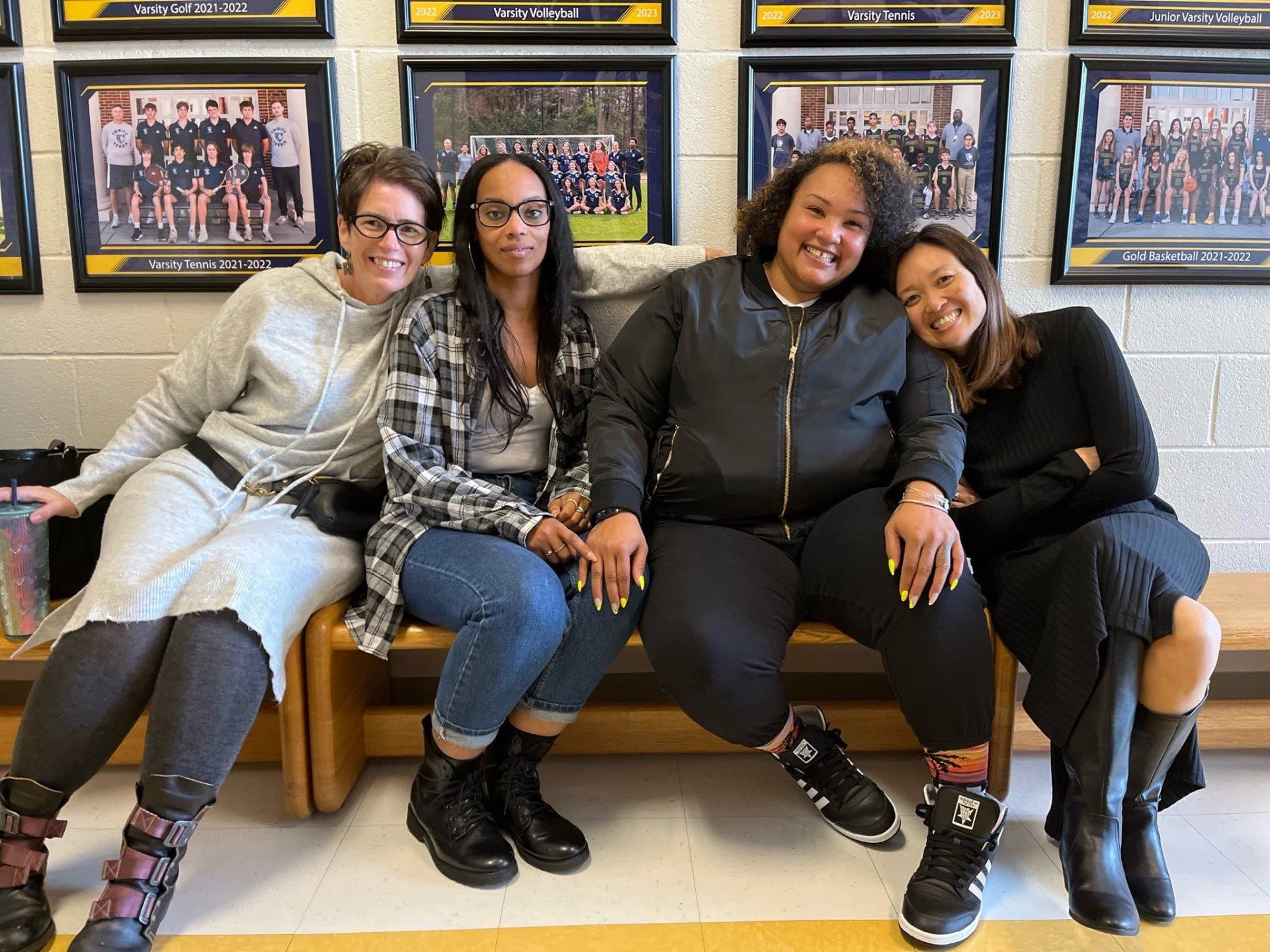 A group of women are sitting on a bench posing for a picture.