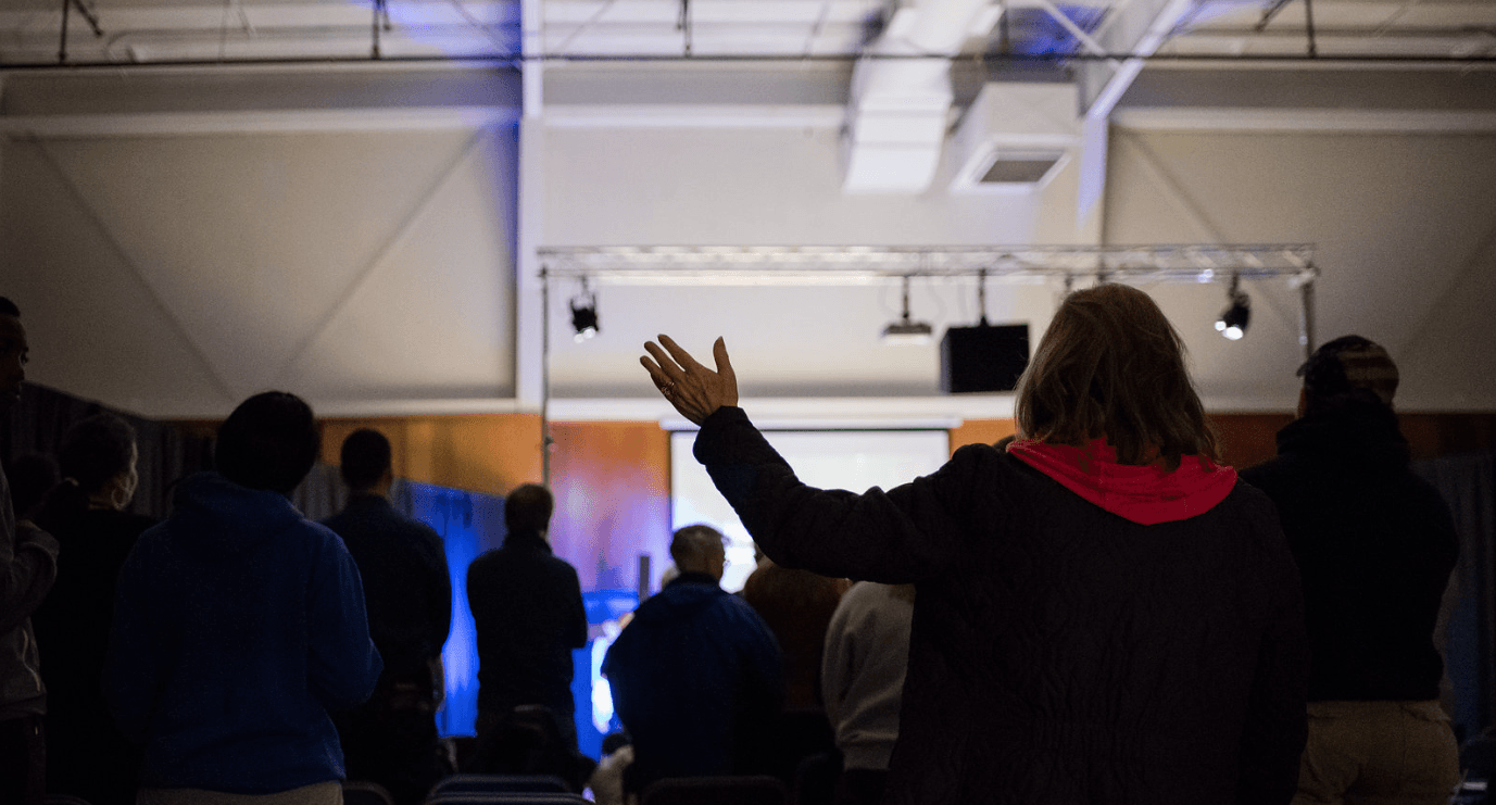 A woman is standing in front of a crowd of people in a dark room.