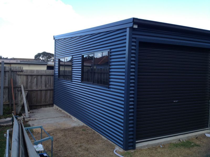 A Blue Garage with a Black Garage Door - Wallan, VIC - Victorian Garages & Barns