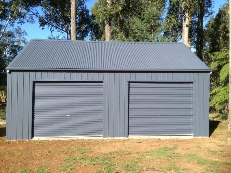 A Garage with Two Roller Doors and a Blue Roof - Wallan, VIC - Victorian Garages & Barns
