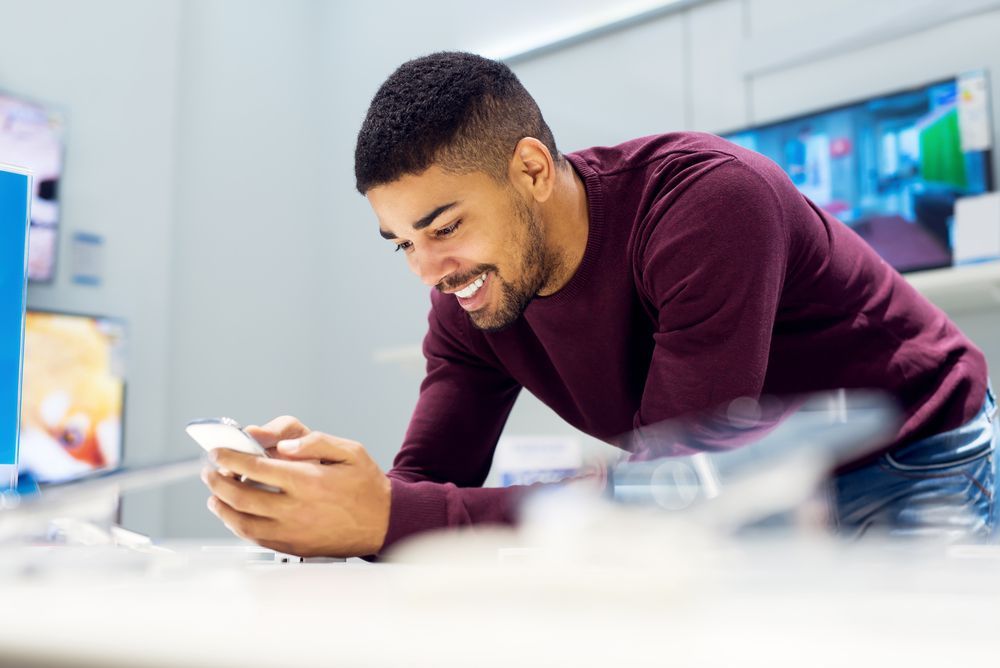 A man is using a cell phone in a store.