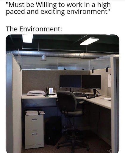 A cubicle with two computer monitors and a printer.