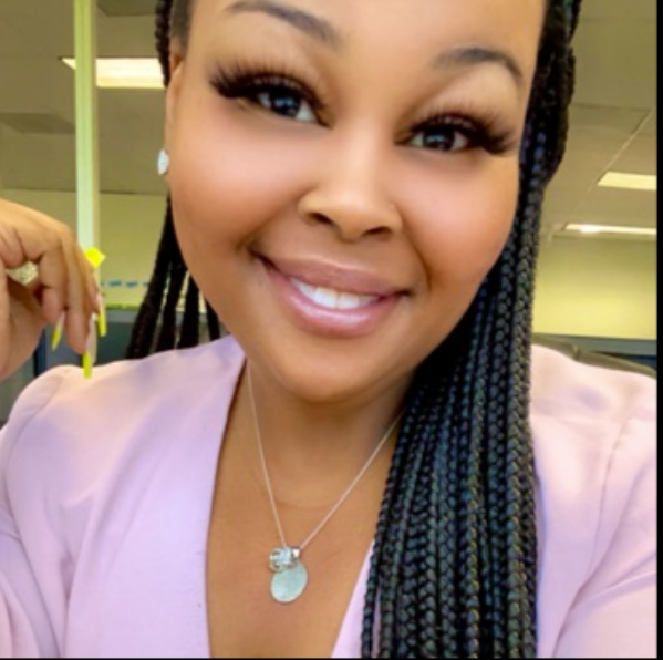 A woman wearing a necklace and earrings smiles for the camera