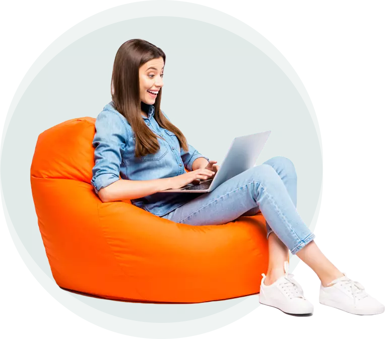 A woman is sitting on an orange bean bag chair using a laptop computer.