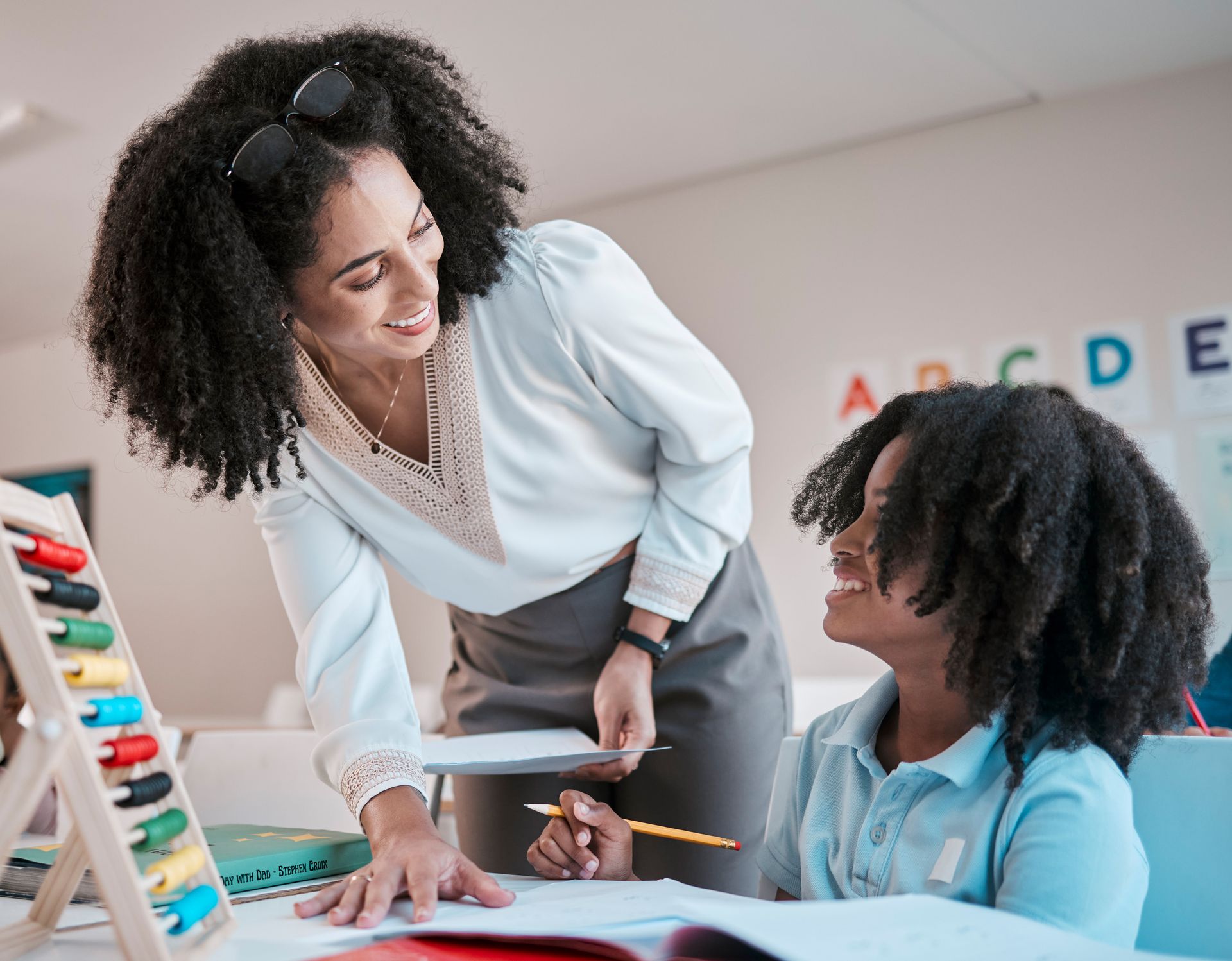 A teacher is helping a student with their homework in a classroom.