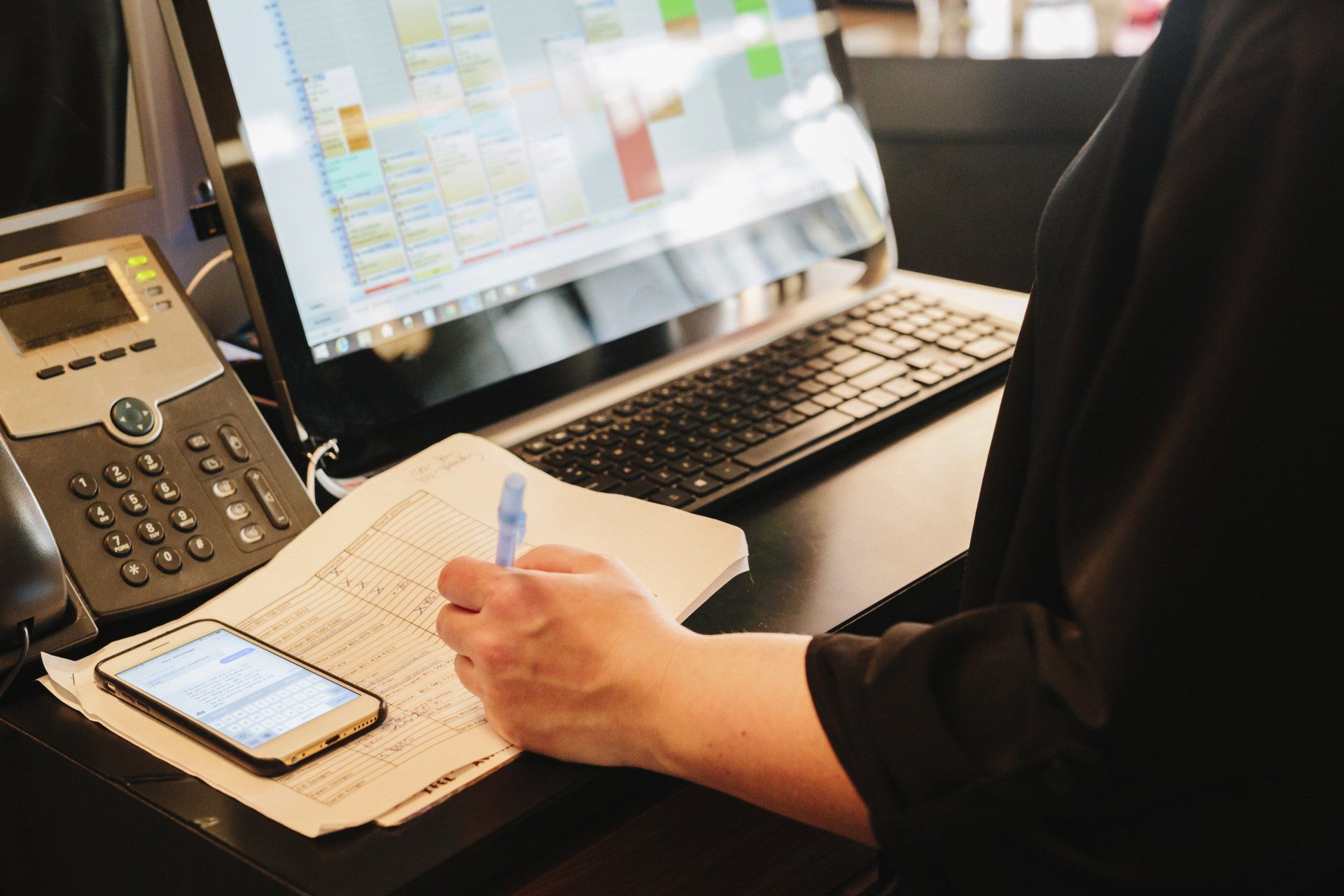 A person is sitting at a desk with a laptop and a phone.