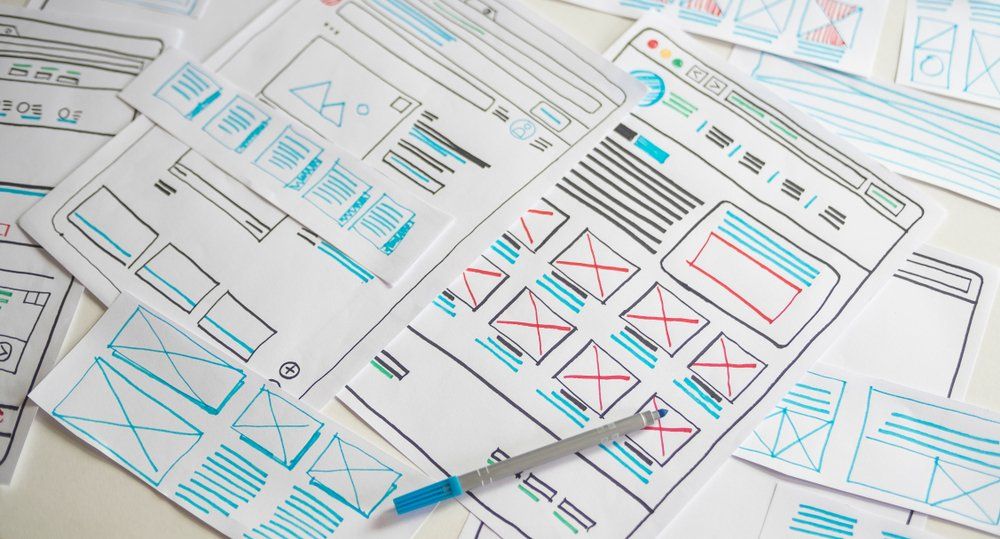 A bunch of papers with drawings on them and a pen on a table.