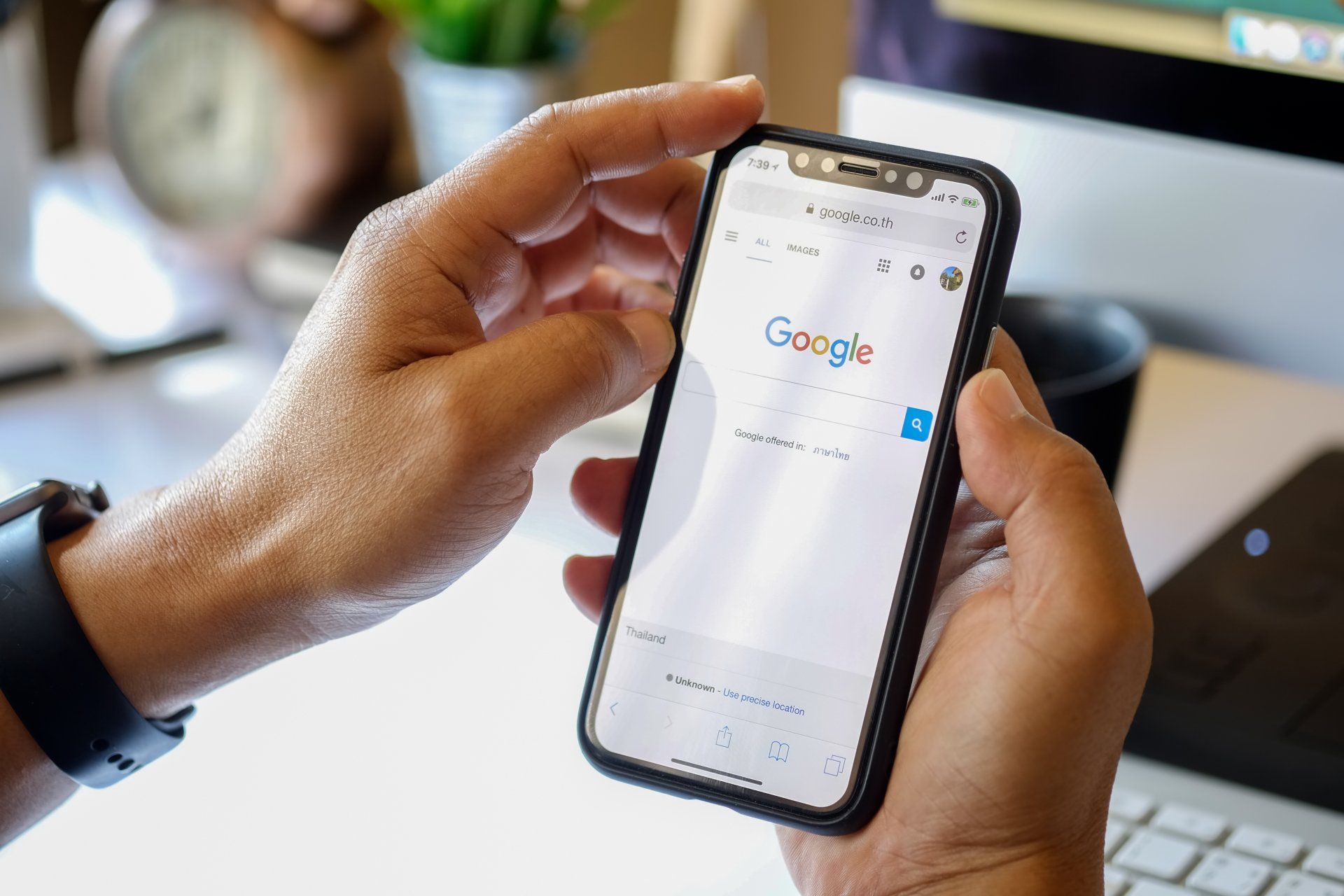 A person is holding a cell phone in their hand and looking at the google search page.