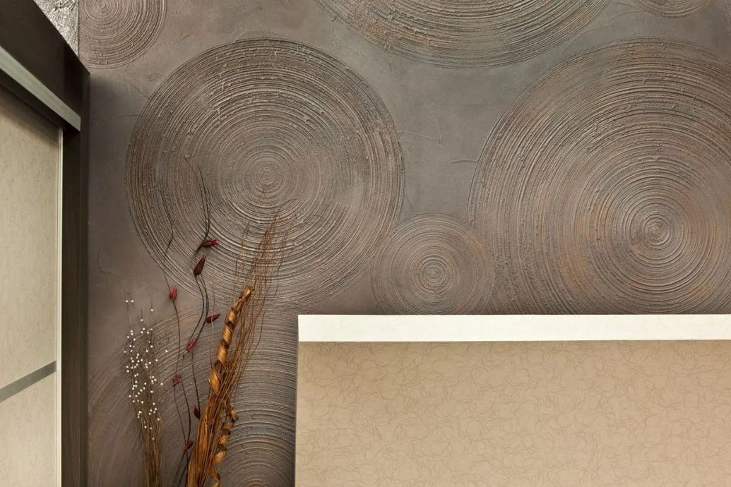Abstract wall art with circular patterns and a beige upholstered chair in a modern interior