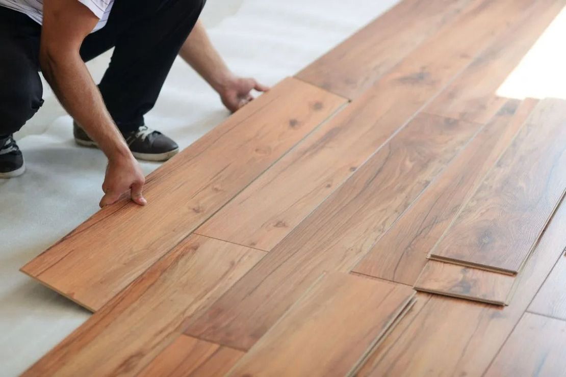 Person installing wood flooring in a bright room