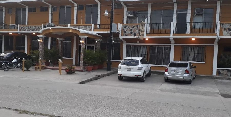 Motel de dos plantas con balcones y coches aparcados delante de las habitaciones.