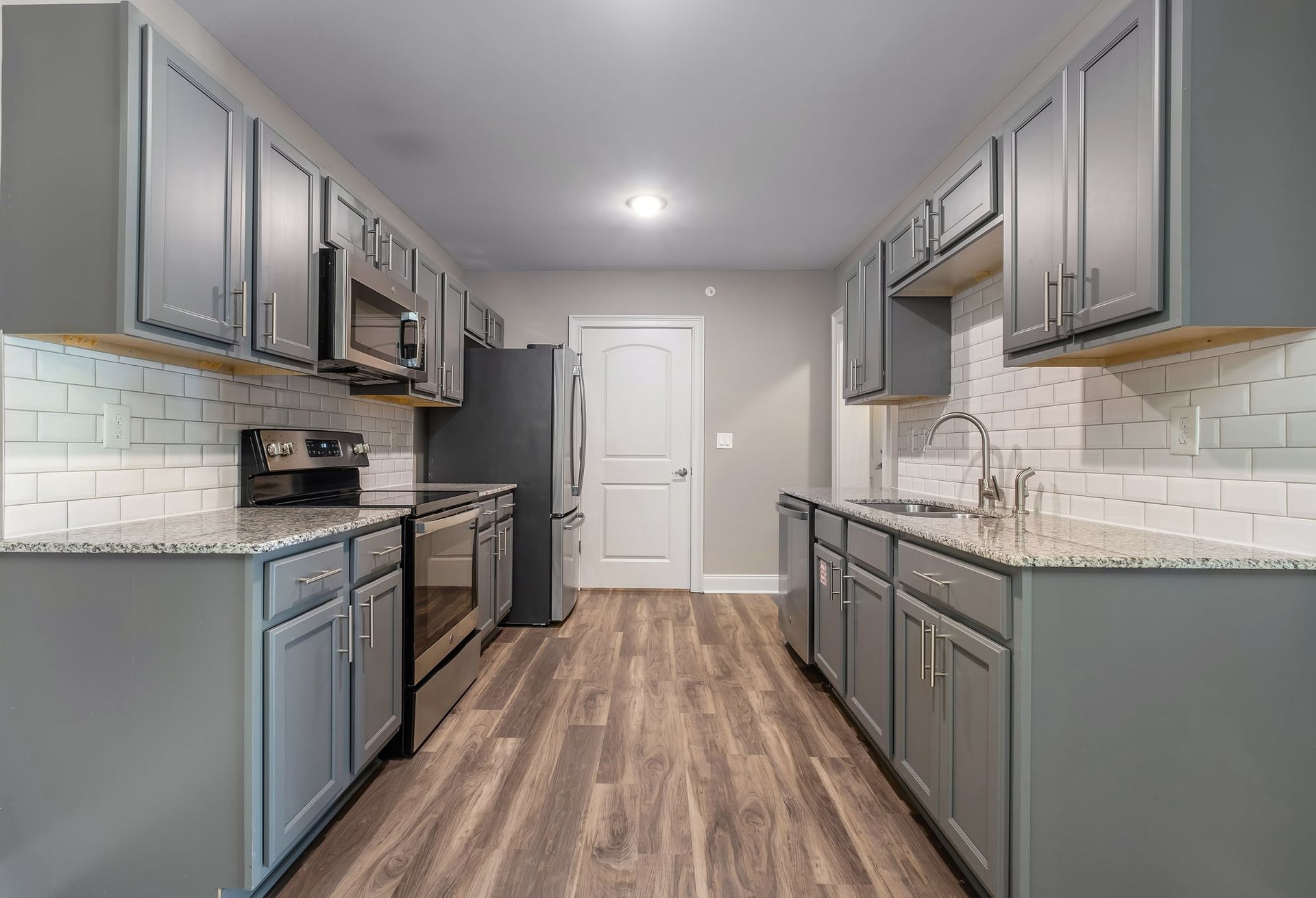 Modern kitchen with sleek gray cabinets, stainless steel appliances, and a granite countertop.