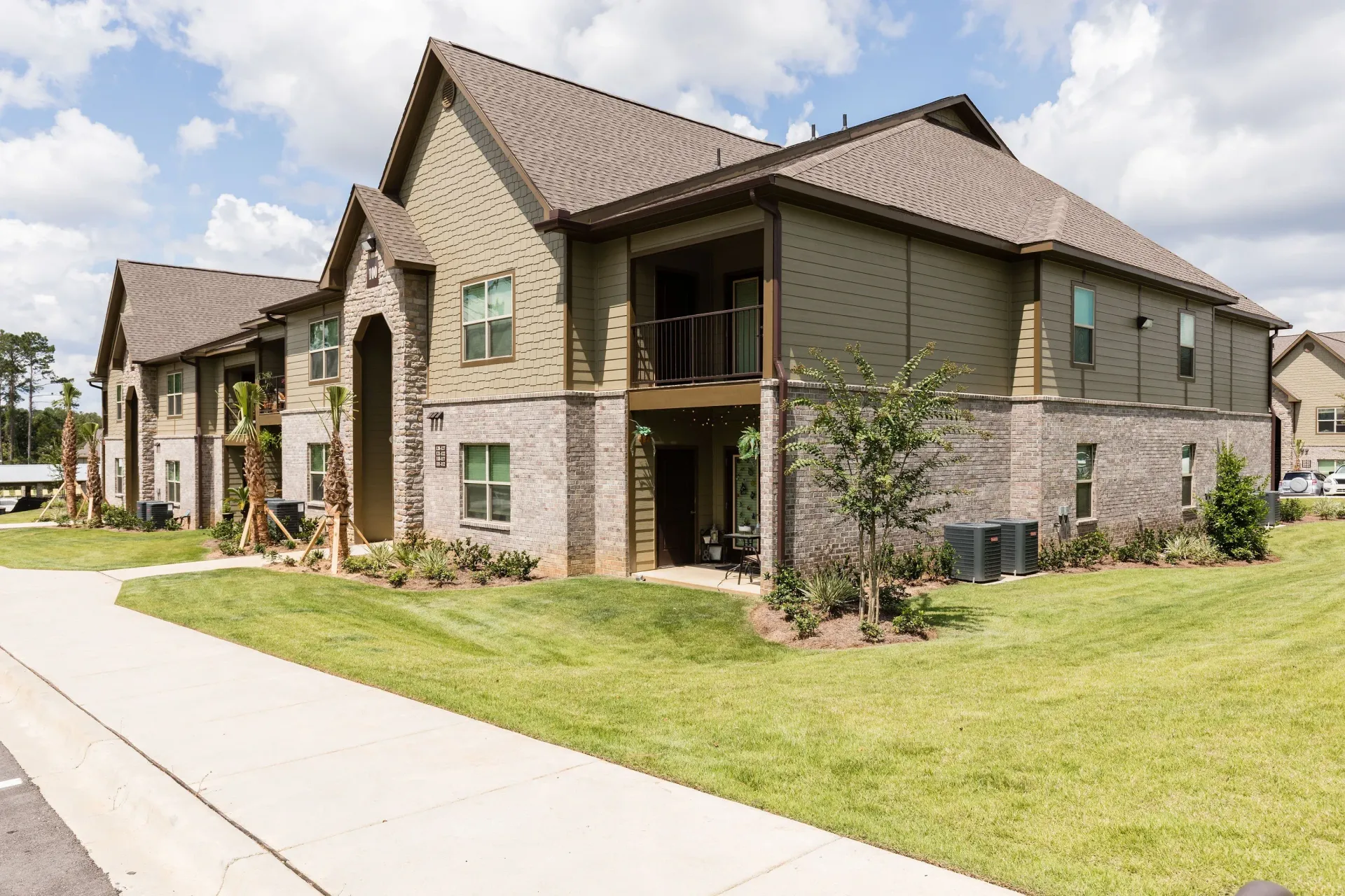 Exterior view of a multi-family apartment building with landscaped lawn and walkway