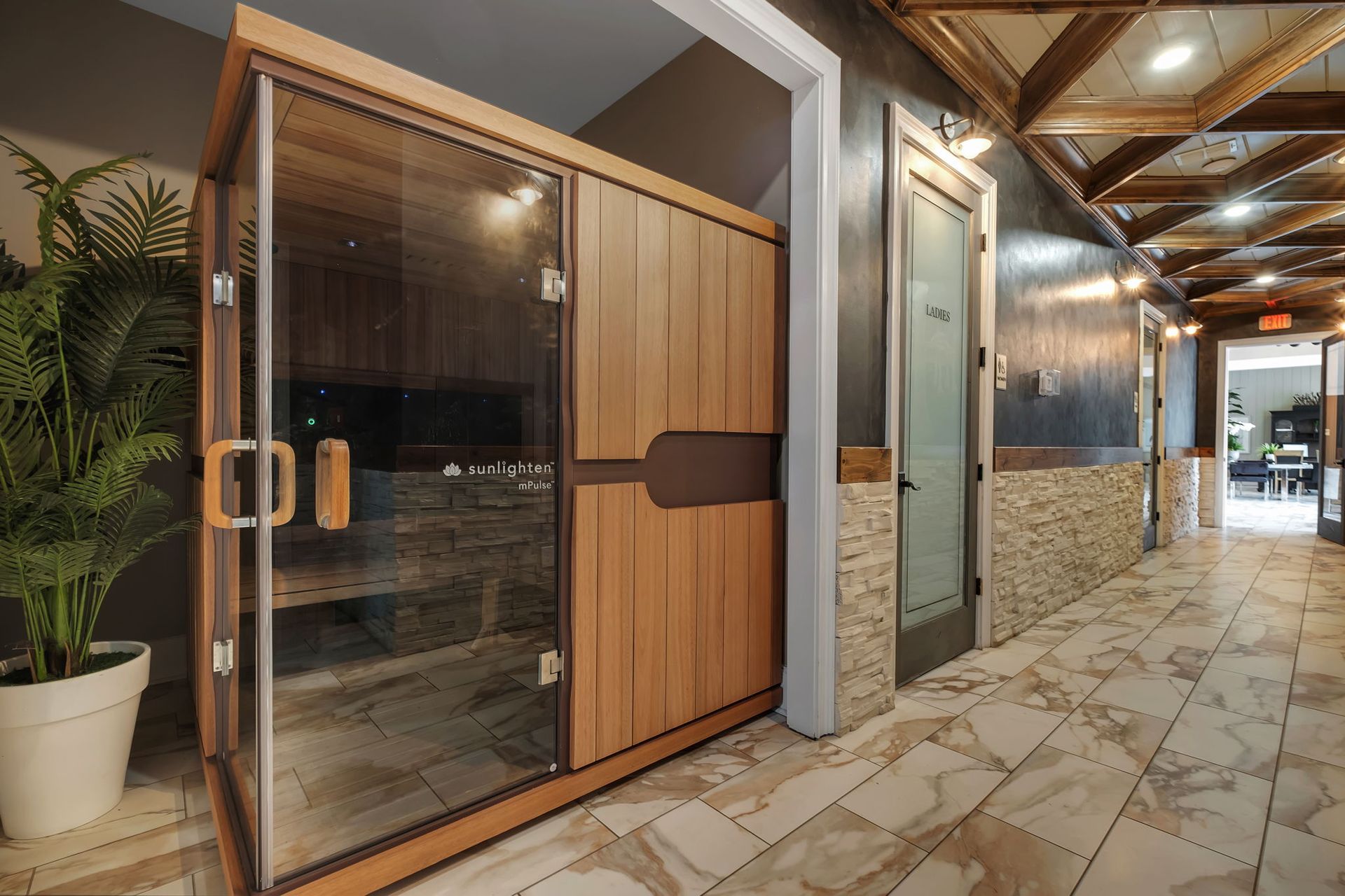 Wood-paneled sauna seen through a glass door with purple lighting.