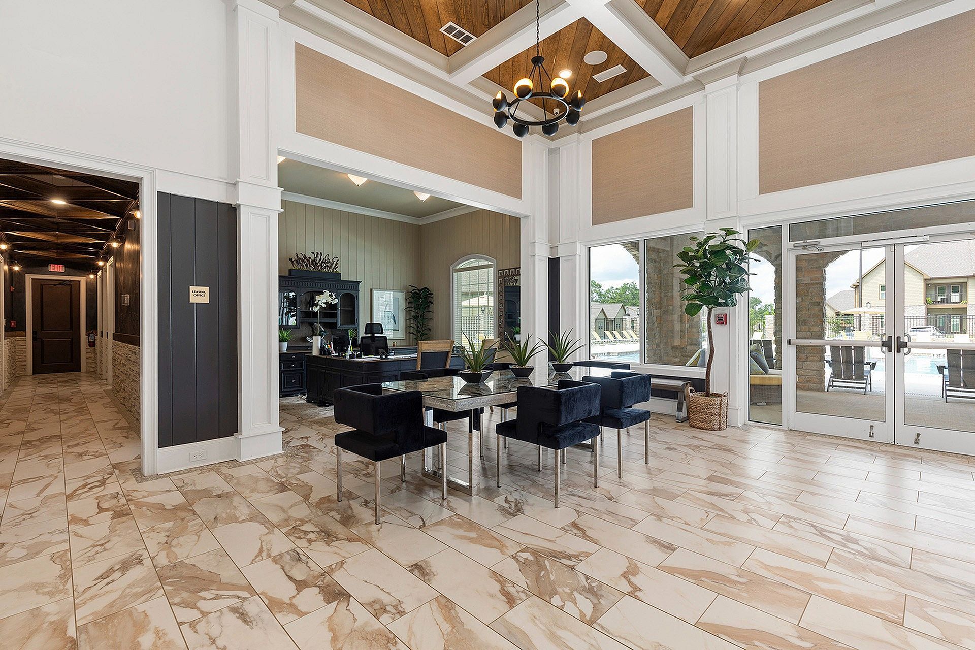 Bright lobby with marble tile, white trim, chandelier, and glass doors to outdoor pool.