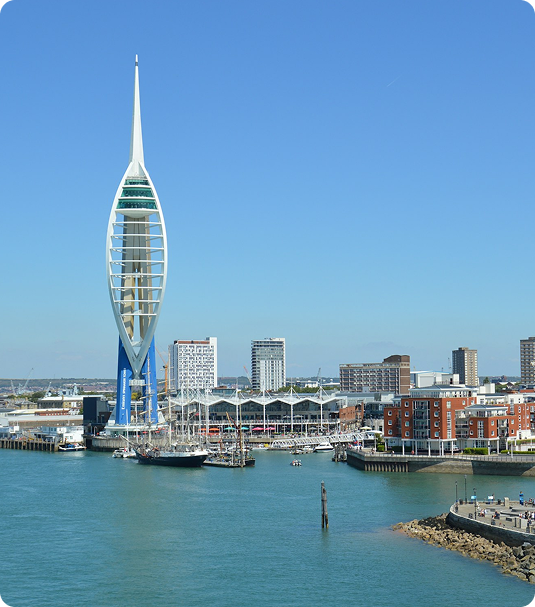 Spinnaker Tower over Portsmouth harbor with boats, waterfront buildings, and blue sky