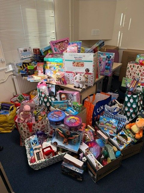 Assorted toys and games piled on tables in a room, with colorful boxes, dolls, and activity sets.