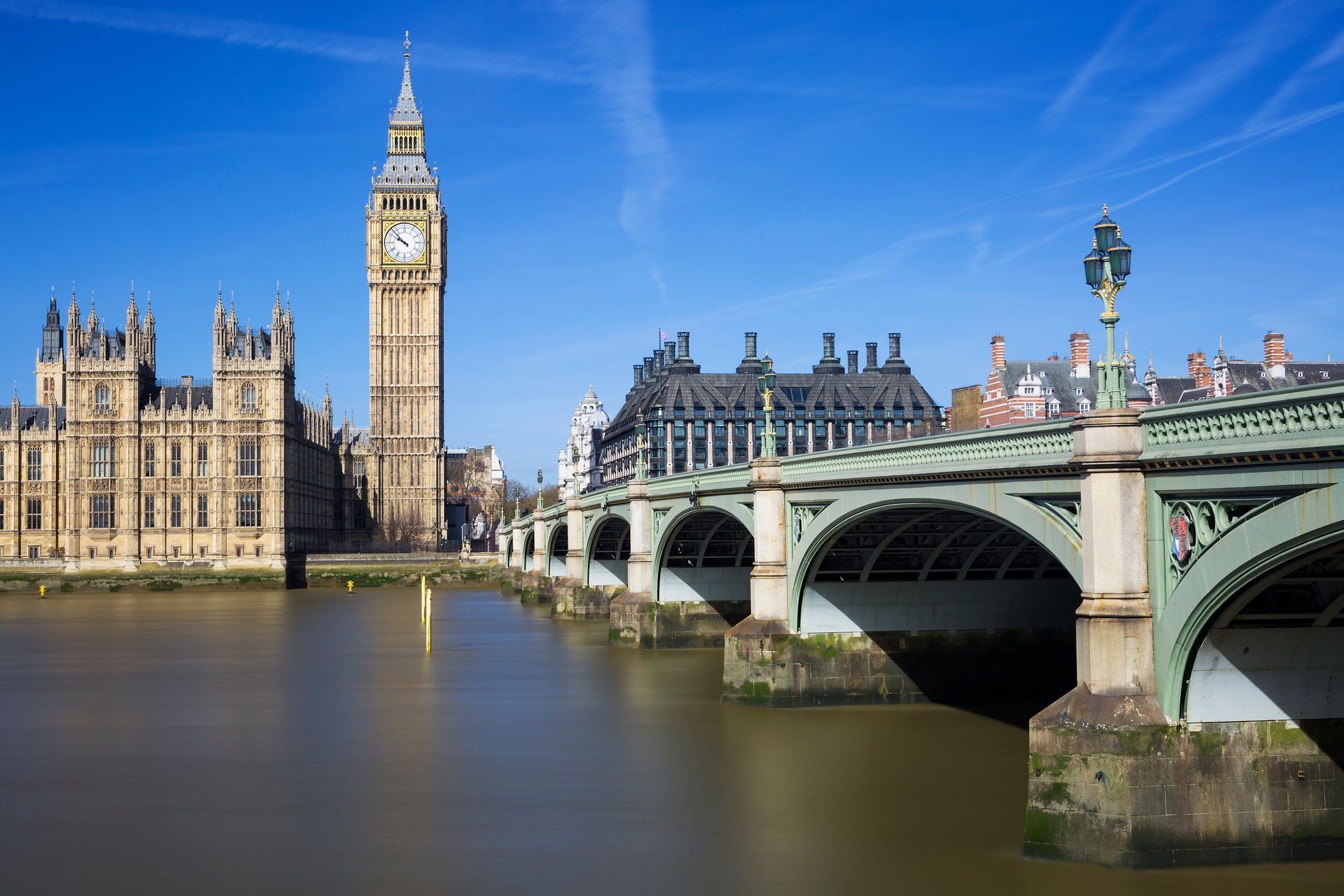 Big Ben and the Palace of Westminster beside Westminster Bridge over the River Thames under a clear blue sky