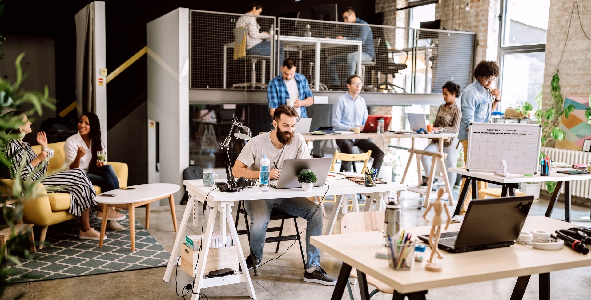 People working and meeting in a bright modern coworking office with desks and laptops