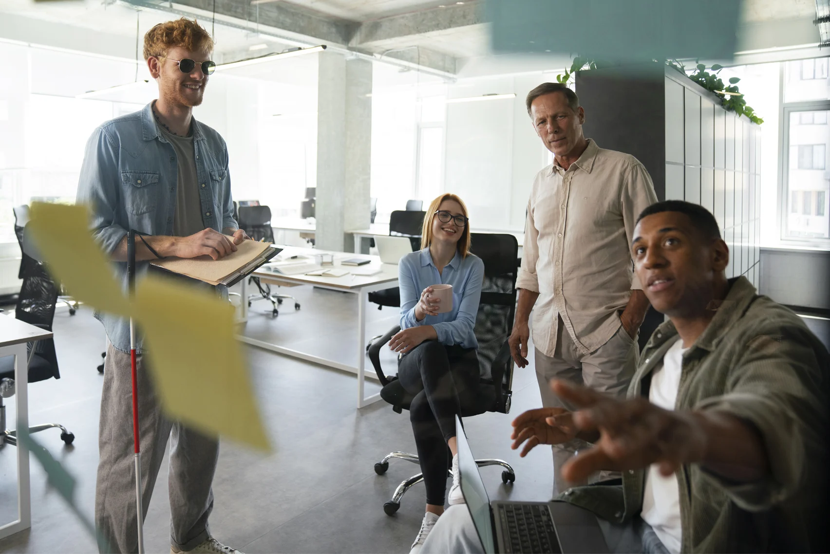 Colleagues gathered in a bright office, discussing ideas around a table with sticky notes.