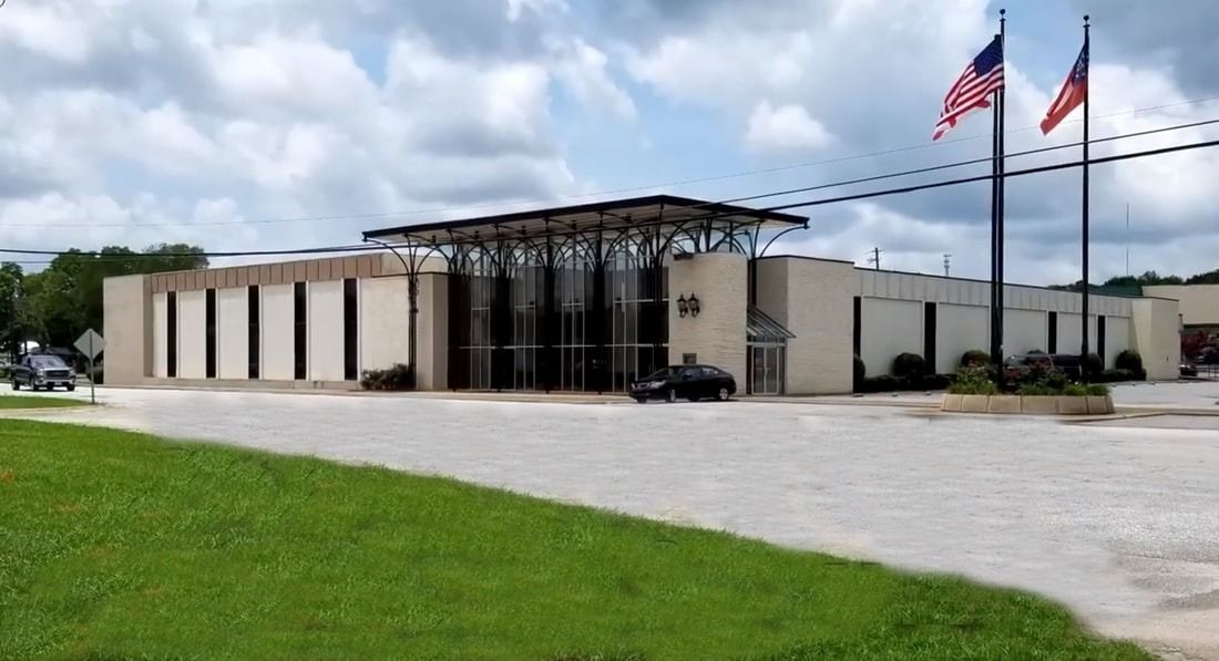 A modern, tan building with a glass entrance and two flagpoles with American flags.