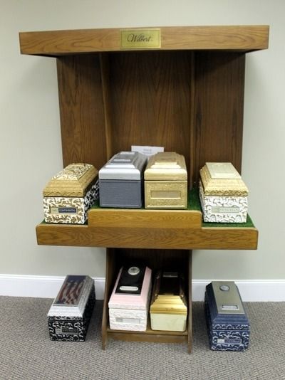 Display of various caskets on wooden shelves in a funeral home.