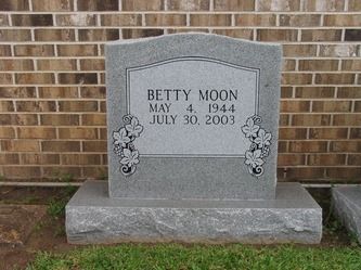 Gray granite headstone for Betty Moon, dates of birth and death: May 4, 1944 - July 30, 2003, against a brick wall.