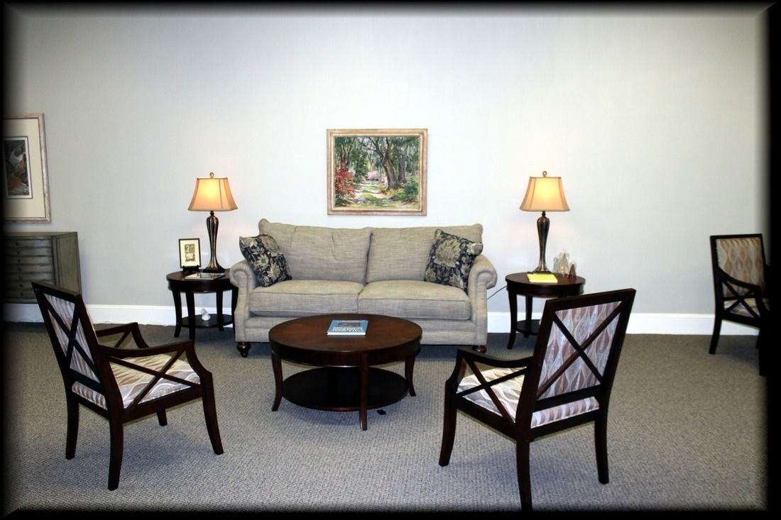 Living room with gray walls, sofa, chairs, lamps, and a painting.