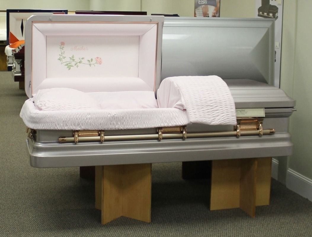 Open gray casket with pink interior on display.