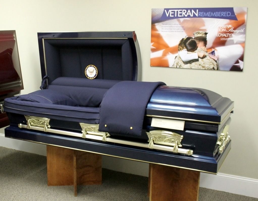 Blue casket with gold handles, interior open, with a military veteran memorial sign.