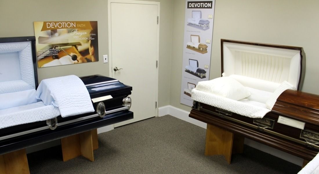 Two open caskets on display in a room, one blue and one brown.