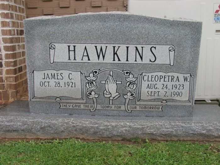 Headstone for James C. and Cleopatra W. Hawkins, gray granite with names, dates, and an engraved design.