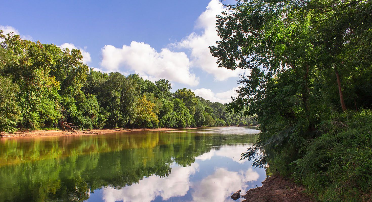 River with trees and blue sky reflecting in the water.