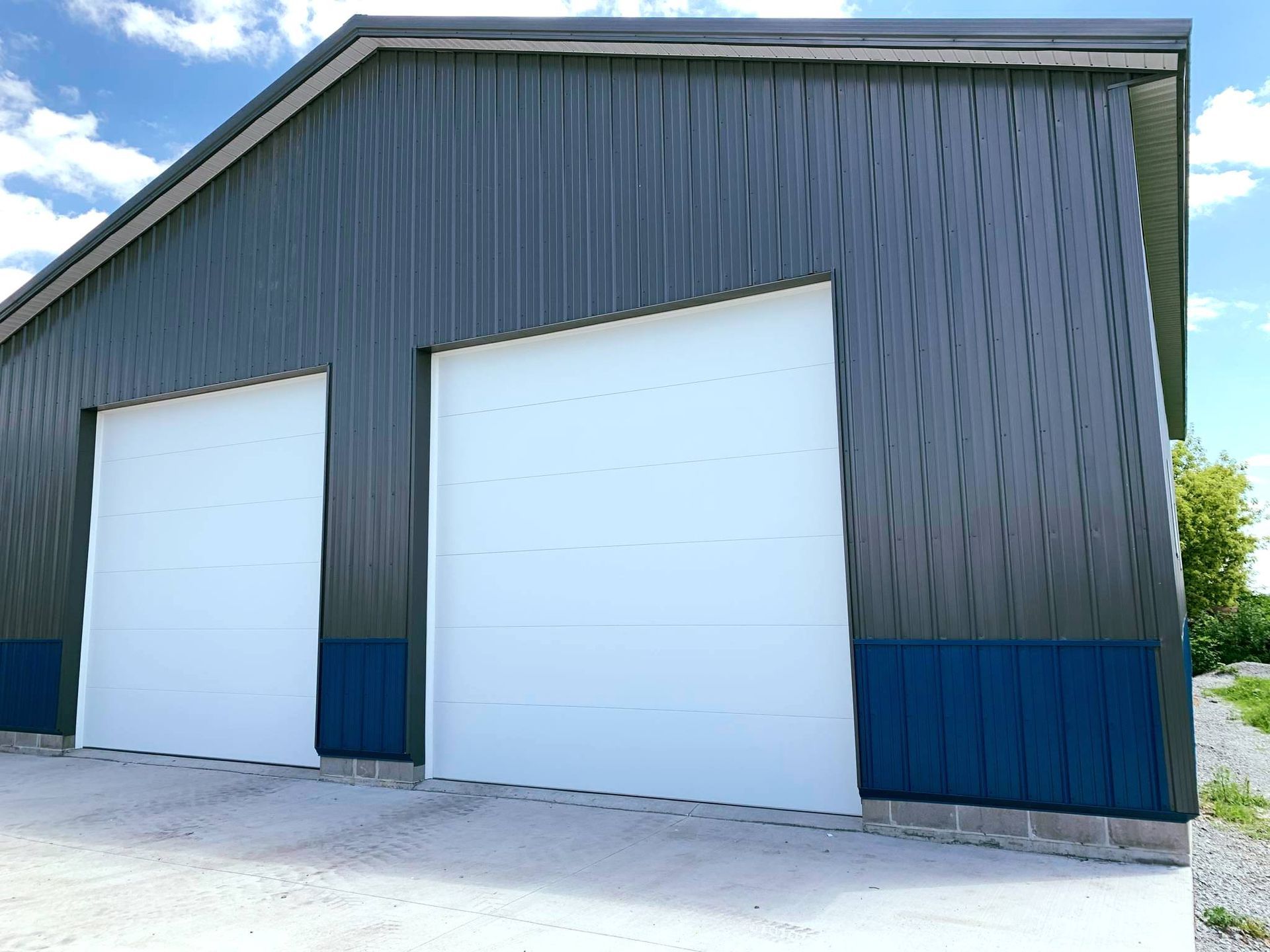 Metal building with two large white garage doors; blue accents and trim.