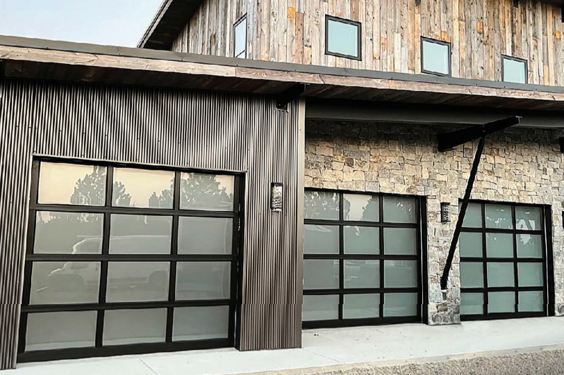 Modern building with three glass garage doors, wood and stone facade.