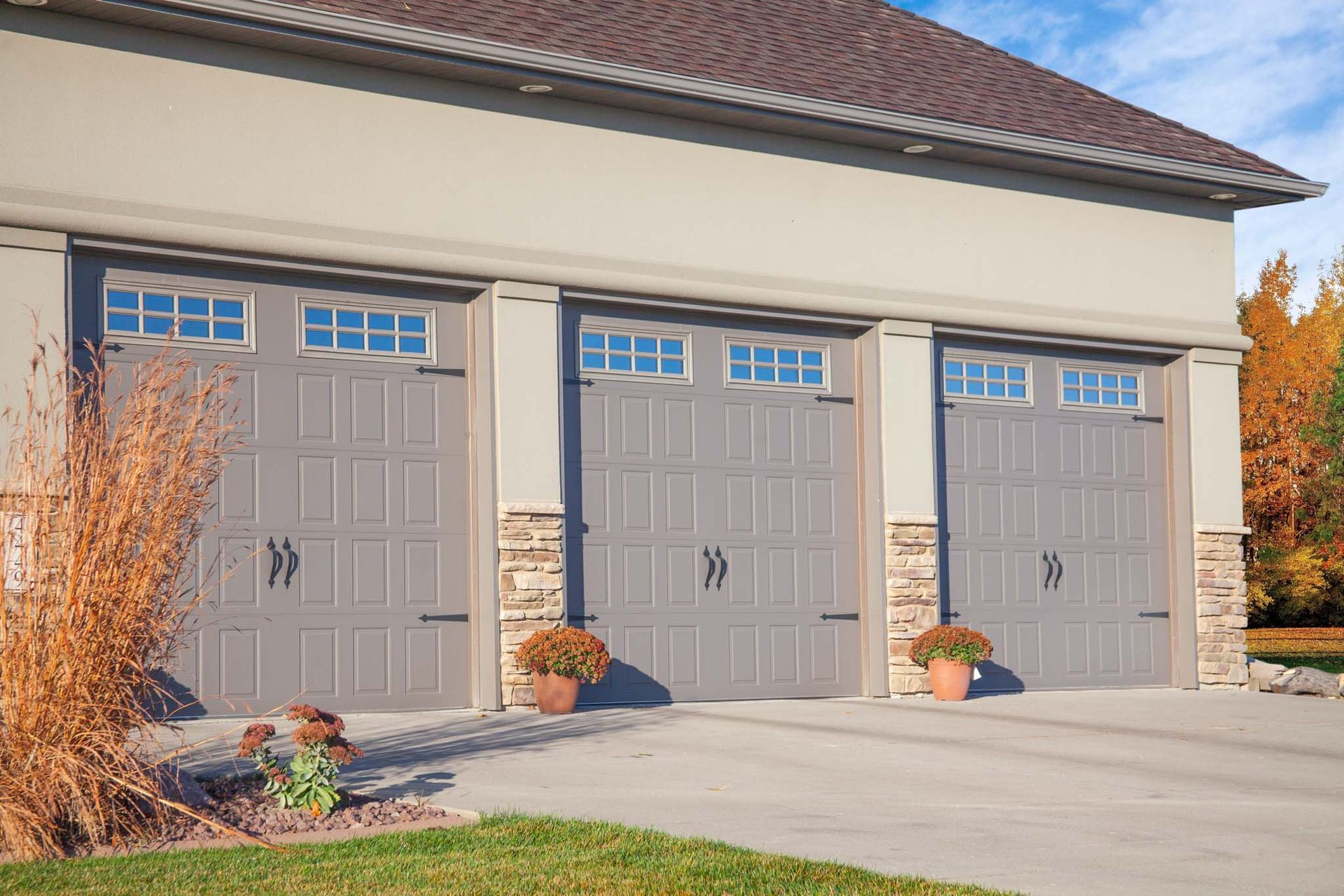 White garage door on a tan brick building with window panes; two brown poles in front.