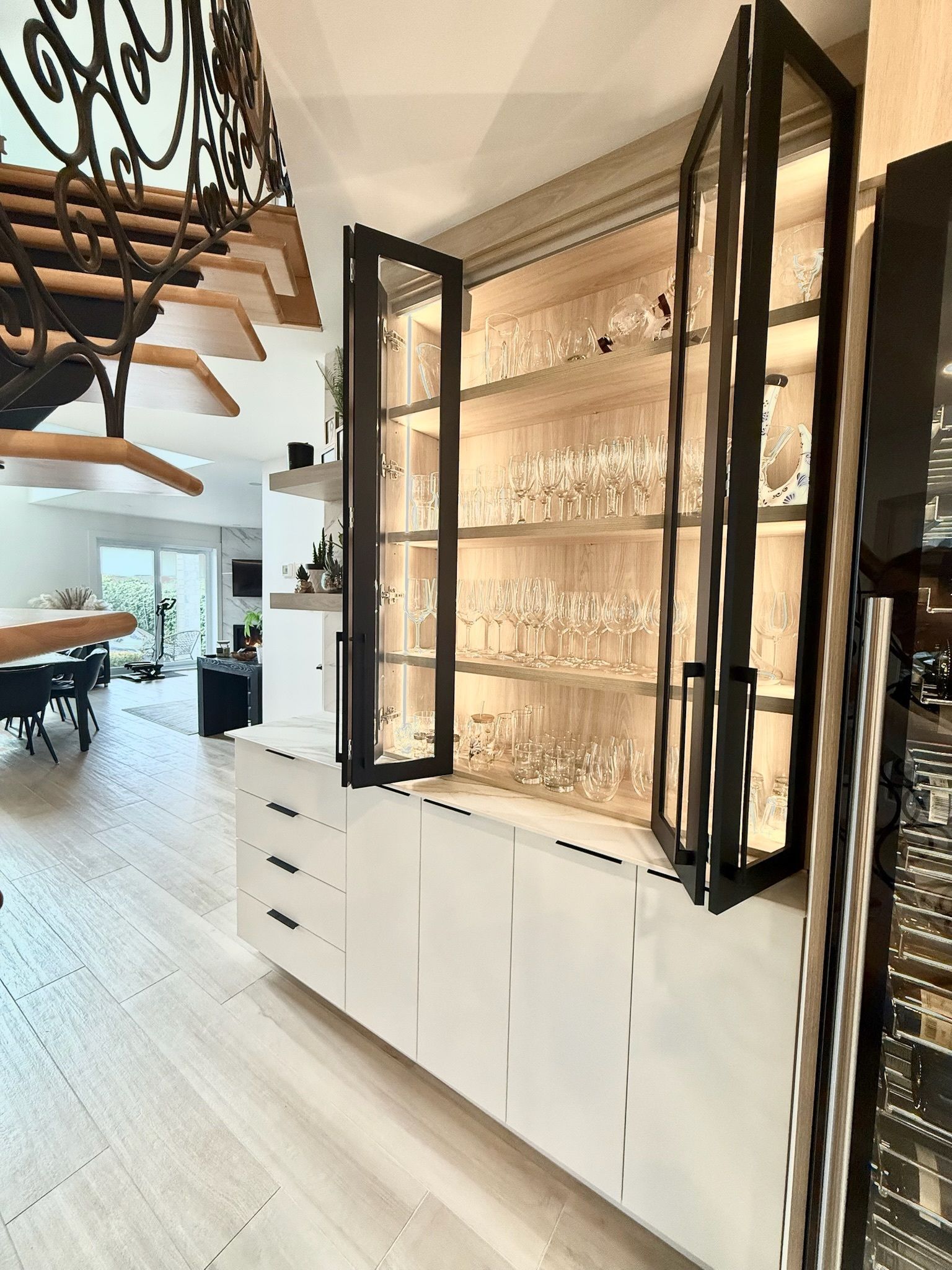 Meuble encastré avec vitrine pour la verrerie, avec tiroirs et éclairage intérieur, à côté de l'escalier.