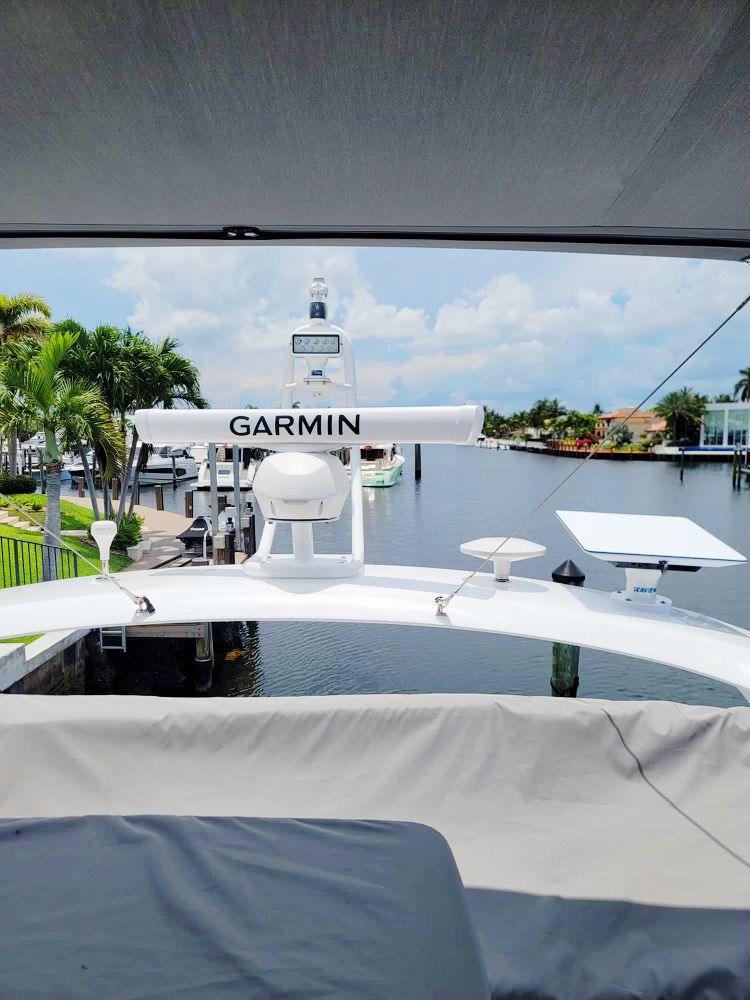Boat deck view with Garmin radar arch, canopy, and calm marina water ahead