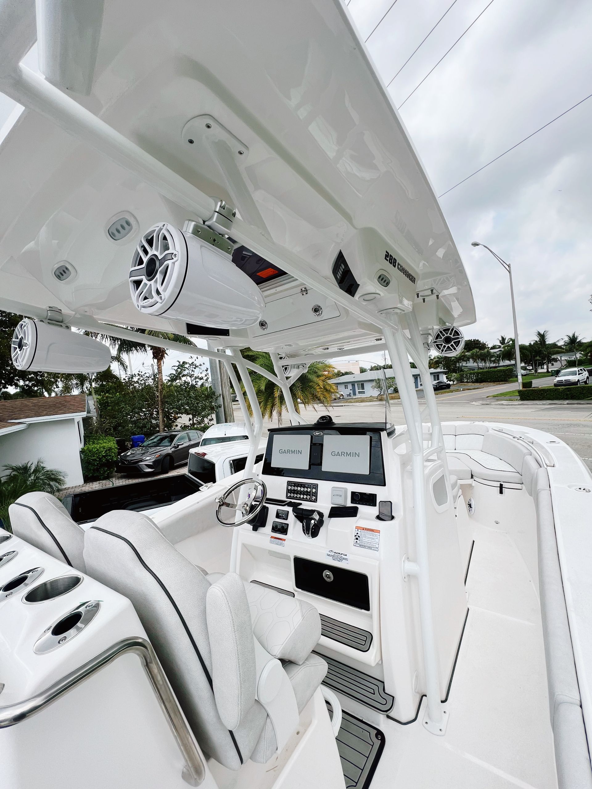 White center console boat helm with a hardtop, speakers, and electronics, parked on a paved lot.