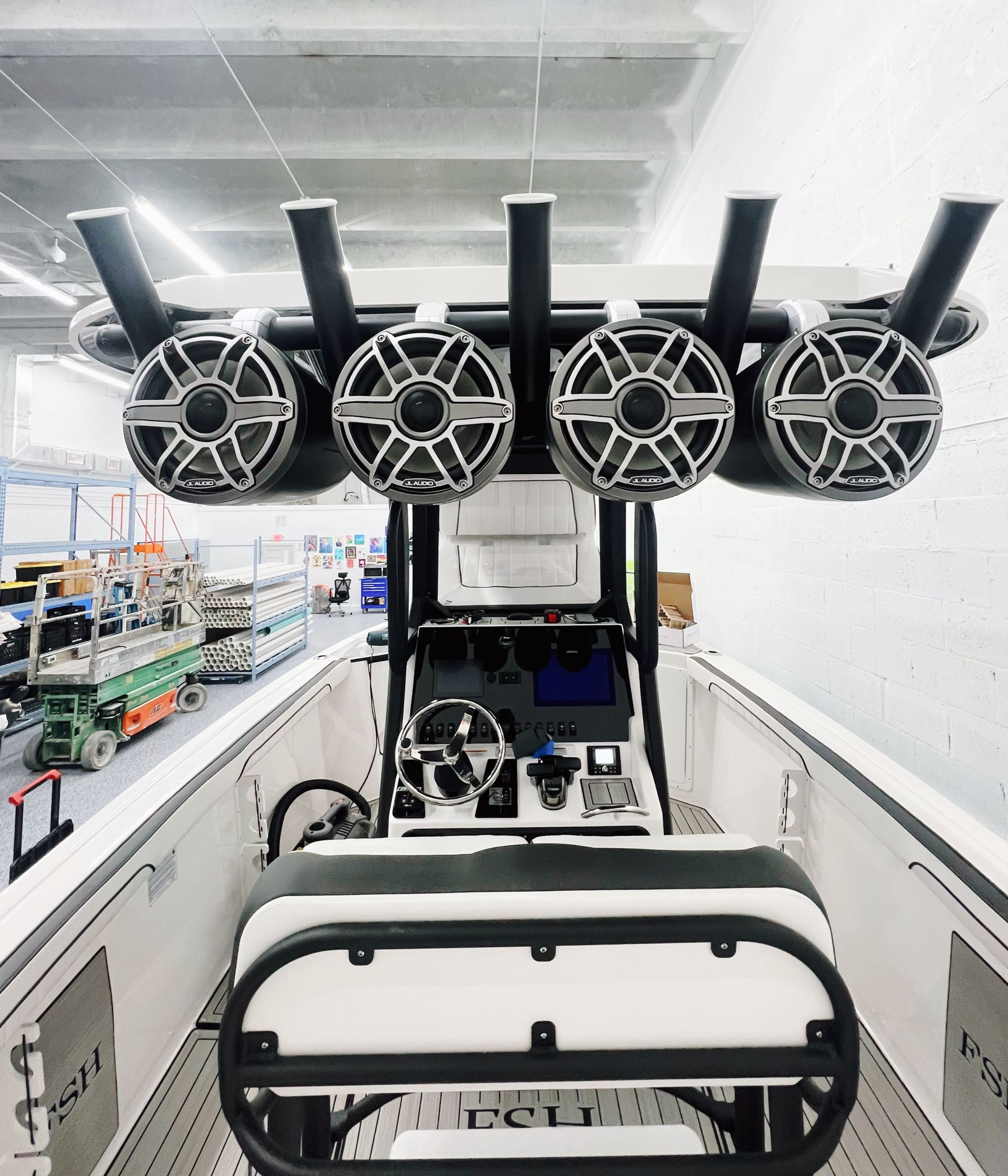 Boat with speaker system on top, black and white interior, in an indoor facility.